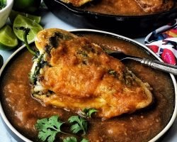 stuffed poblano pepper with red sauce on black plate
