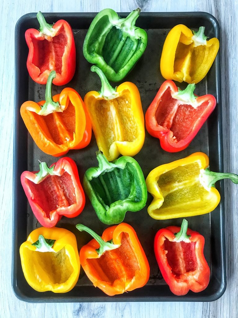 Raw sliced green, red, orange, and yellow bell peppers.