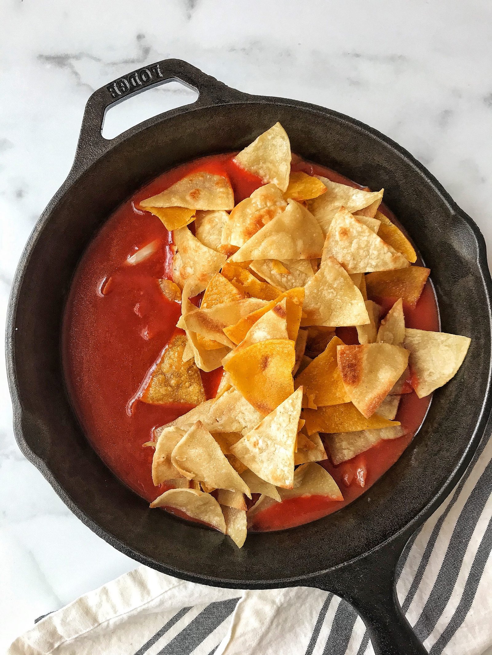 Tortilla chips with red sauce in cast iron skillet