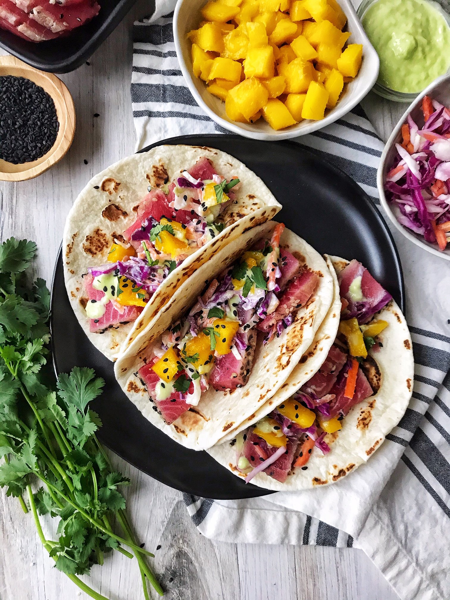 Ahi Tuna tacos with garlic-ginger slaw, mango, and wasabi sauce. Sesame seeds, mango, cilantro on the side.
