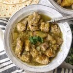 Pokr chile verde in white bowl, flour tortillas on side