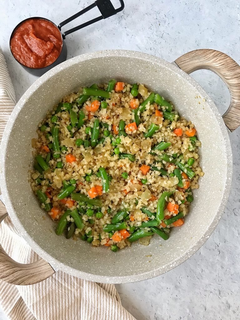 Pan with cauliflower rice and mixed vegetables. Tomato sauce on the side.