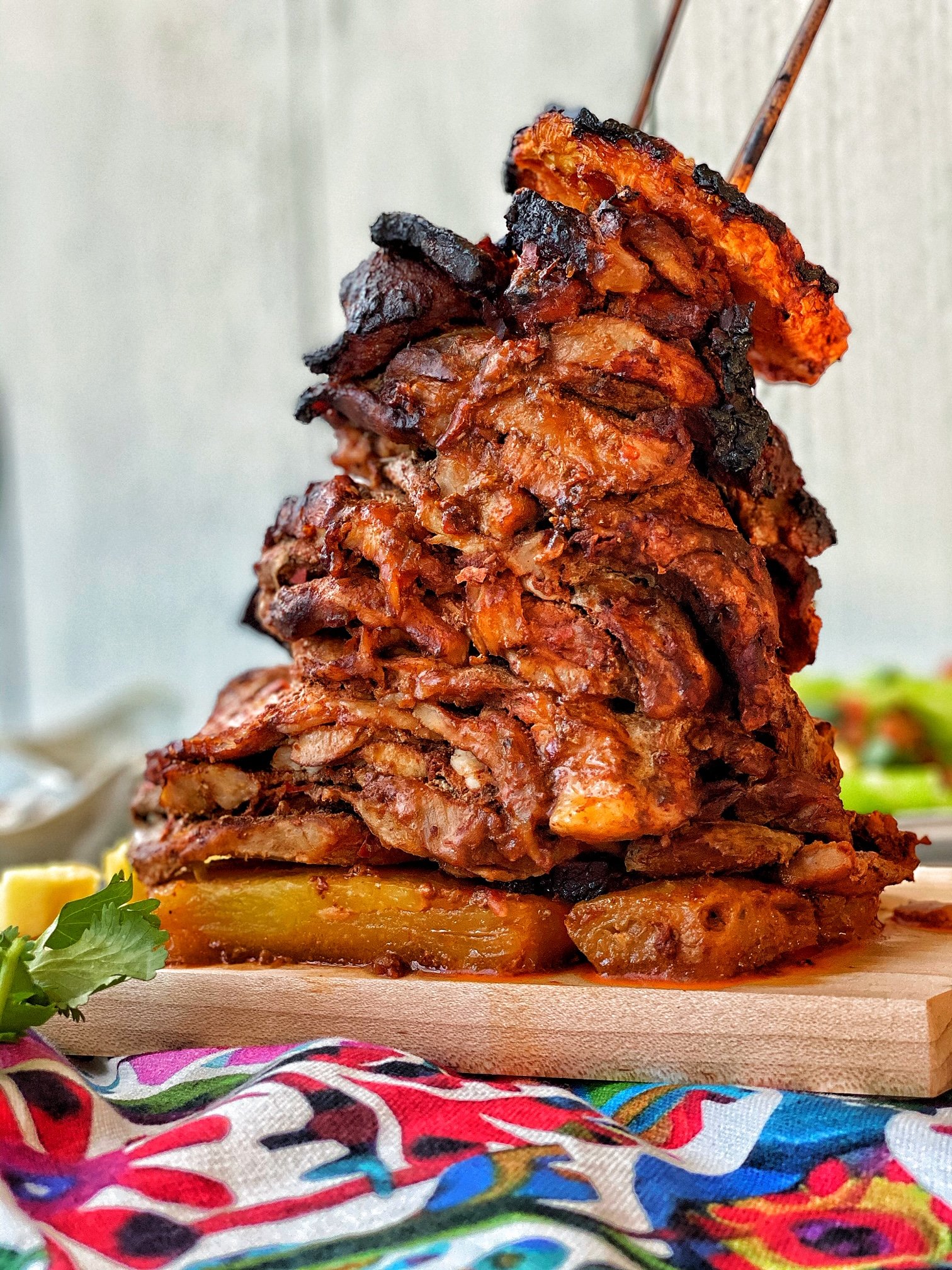 Carne Al Pastor stacked on skewers with pineapple slices.