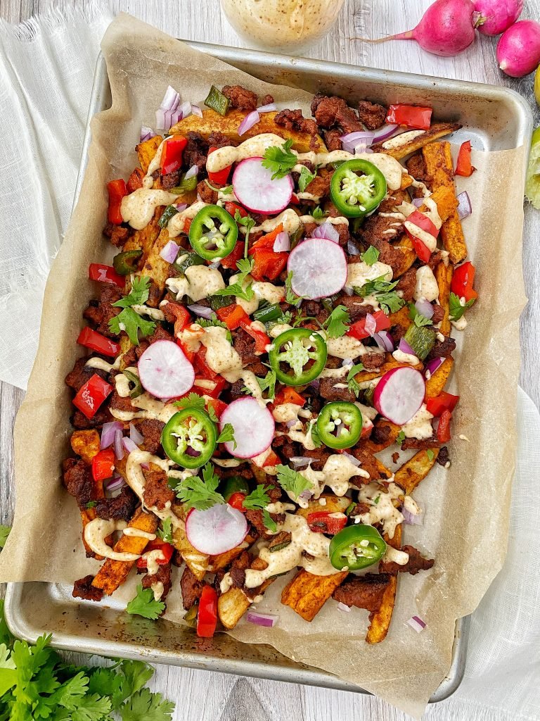 Pan of loaded chorizo fries with red peppers, radishes, jalapenos, and onion