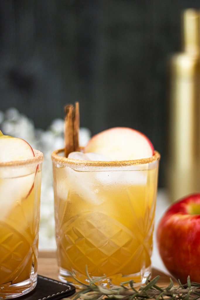 Apple cider margarita with apple slice and cinnamon stick garnish. Apple on side