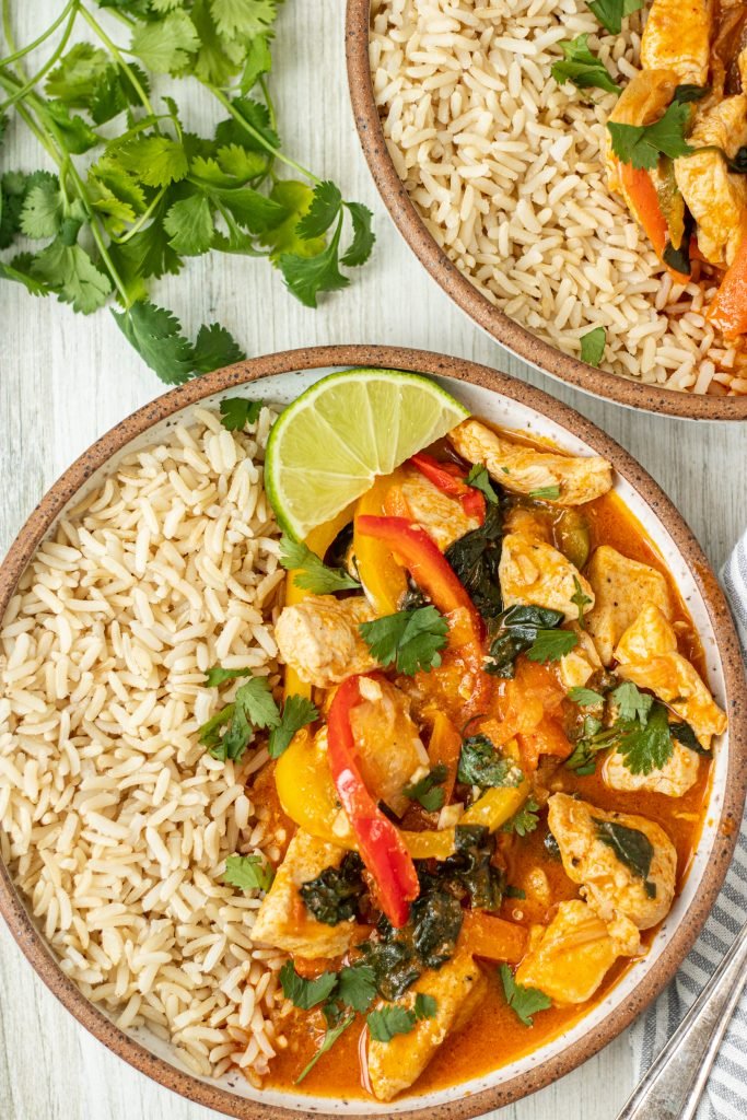Bowl with Thai Lemongrass Curry with brown rice and lime garnish. Cilantro garnish