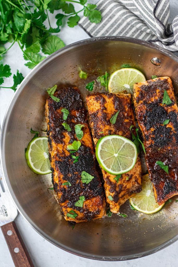 Chili Lime Salmon in stainless steel pan. Lime and cilantro garnish